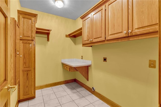 clothes washing area featuring cabinet space, light tile patterned flooring, hookup for an electric dryer, and baseboards