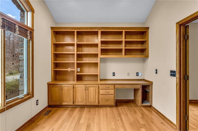 unfurnished office featuring built in study area, light wood finished floors, and visible vents