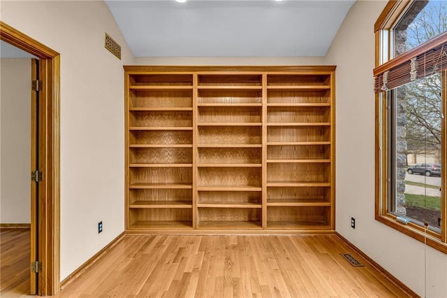 interior space featuring baseboards, vaulted ceiling, and light wood-type flooring
