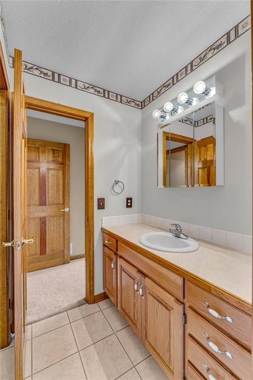bathroom with a textured ceiling, tile patterned floors, and vanity