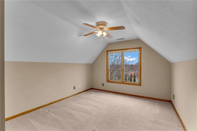 additional living space with visible vents, carpet, baseboards, and vaulted ceiling