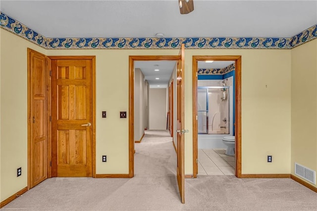 unfurnished bedroom featuring light colored carpet, baseboards, visible vents, and ensuite bath