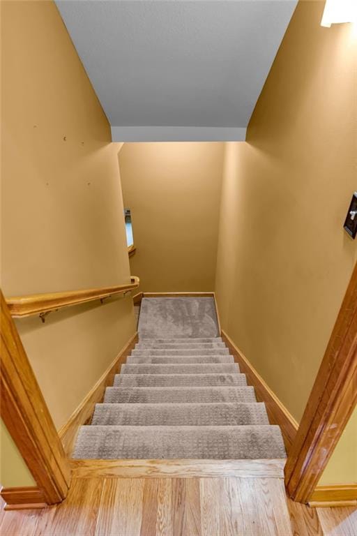 staircase featuring baseboards and wood finished floors