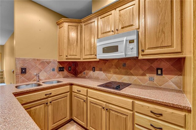 kitchen with a sink, decorative backsplash, white microwave, and black electric stovetop