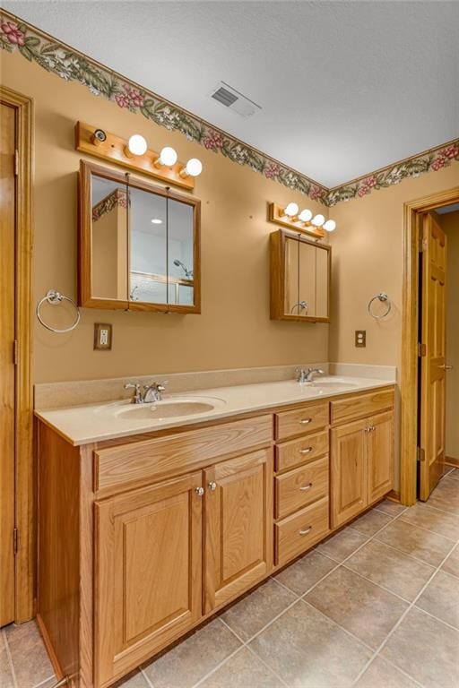 bathroom with double vanity, visible vents, a sink, and tile patterned flooring
