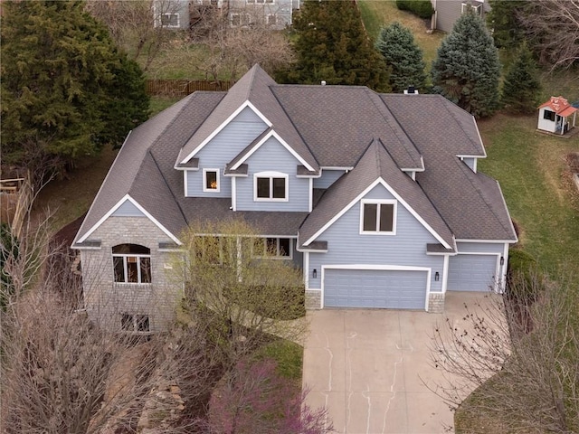 craftsman inspired home featuring a front yard, concrete driveway, an attached garage, a shingled roof, and stone siding