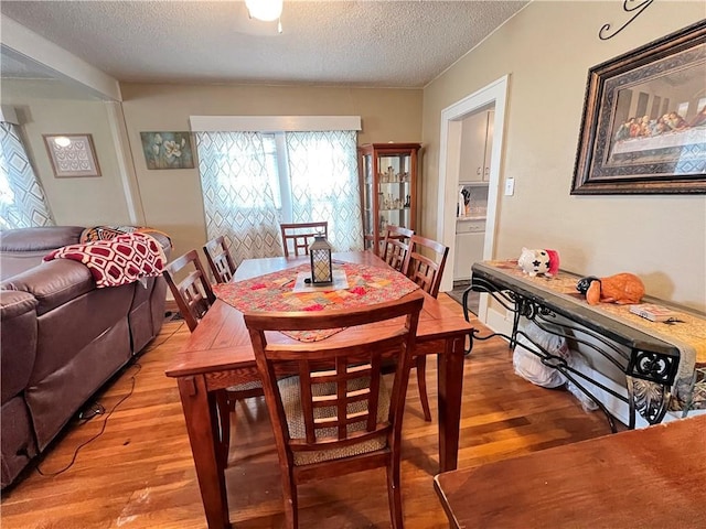 dining space featuring light wood finished floors and a textured ceiling