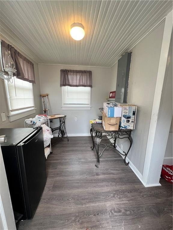 interior space with electric panel, baseboards, and wood finished floors