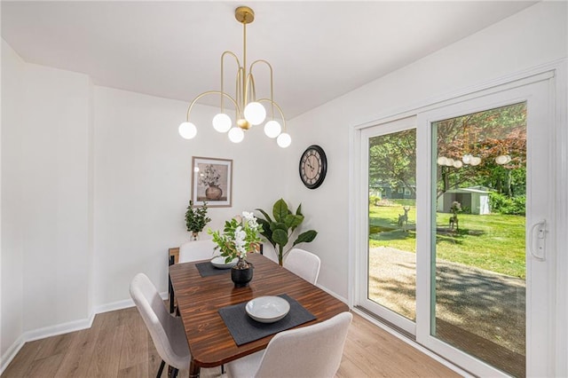 dining space with light wood-style floors, a chandelier, and baseboards