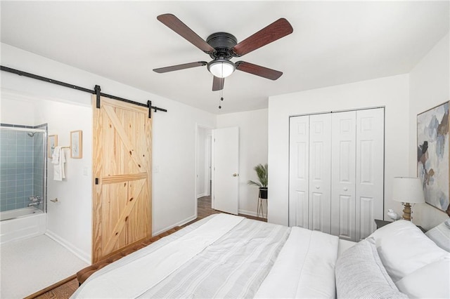 bedroom with a barn door, a closet, baseboards, and ceiling fan
