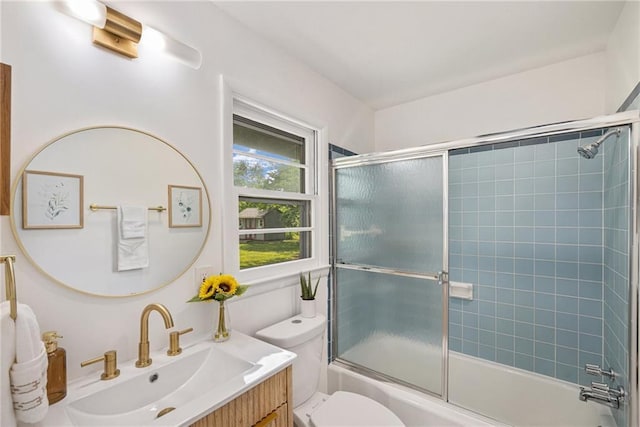 full bath with toilet, vanity, and bath / shower combo with glass door
