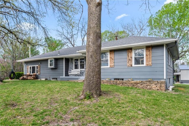 rear view of house with a lawn and roof with shingles