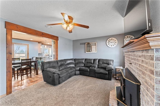 carpeted living area featuring a ceiling fan and a textured ceiling