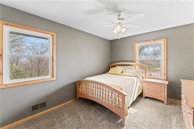 bedroom with visible vents, a textured wall, light carpet, baseboards, and a textured ceiling
