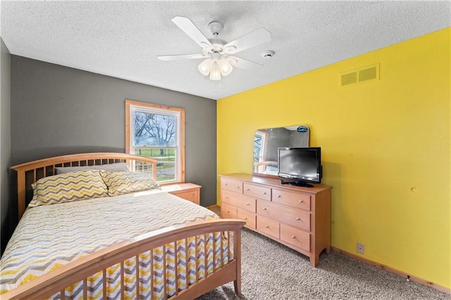 bedroom with visible vents, a textured ceiling, ceiling fan, and light carpet