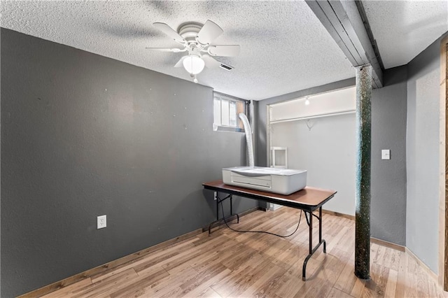 home office with a textured ceiling, visible vents, ceiling fan, and wood finished floors