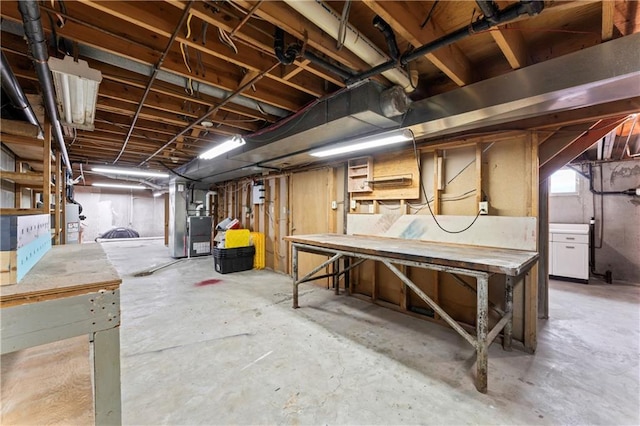 below grade area featuring heating unit, gas water heater, and a workshop area
