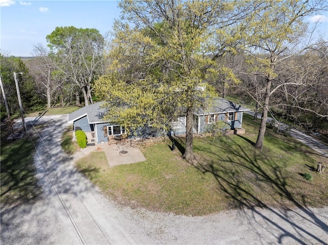 view of front of home featuring dirt driveway, a patio area, and a front yard