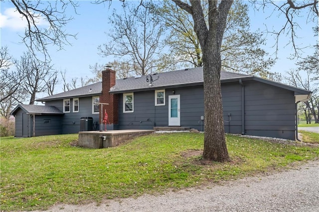 back of property featuring a lawn, a chimney, and cooling unit