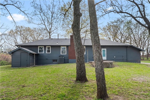 back of property with a lawn, central AC, and a chimney
