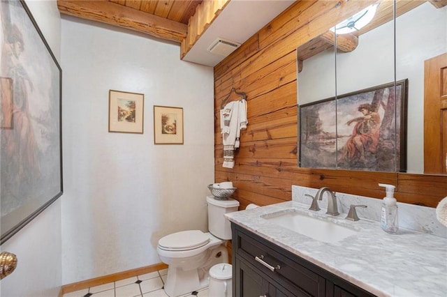 bathroom featuring vanity, wood walls, toilet, baseboards, and beamed ceiling