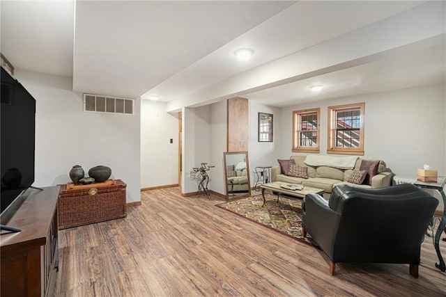 living area featuring wood finished floors, baseboards, and visible vents