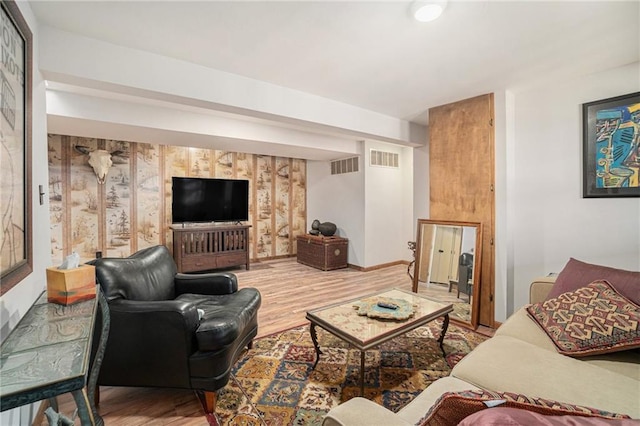 living area featuring baseboards, visible vents, and wood finished floors