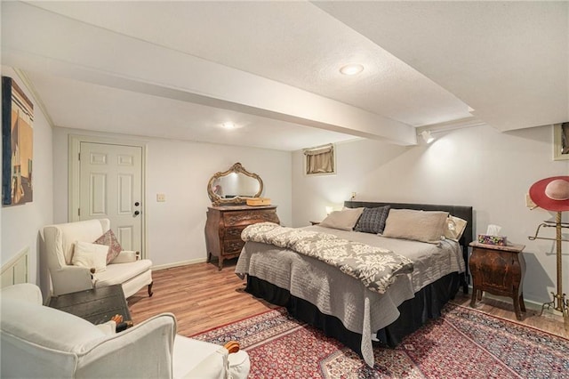 bedroom with baseboards, light wood finished floors, and a textured ceiling