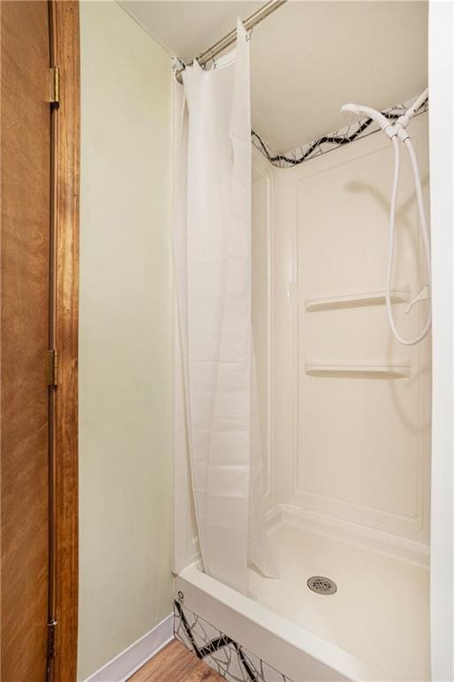 full bath with baseboards, wood finished floors, and a shower stall