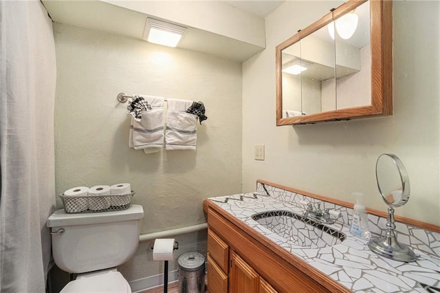 bathroom featuring toilet, vanity, and baseboards