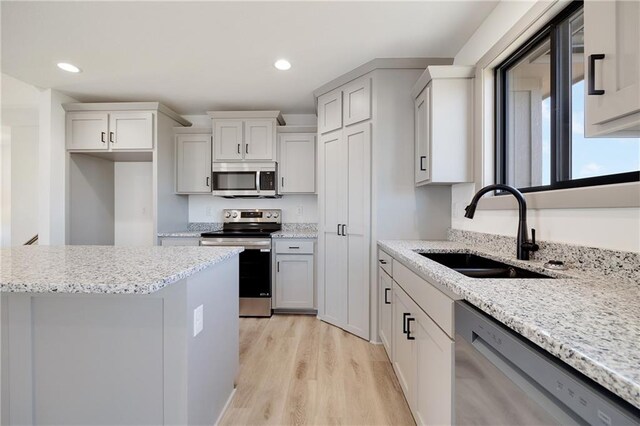 815 W Solomon Dr, Lone Jack, MO 64086 - kitchen featuring appliances with stainless steel finishes, a sink, light wood-style floors, recessed lighting, and light stone countertops