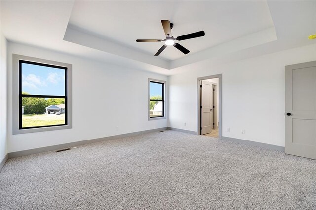 815 W Solomon Dr, Lone Jack, MO 64086 - unfurnished bedroom featuring a tray ceiling, light colored carpet, baseboards, and a ceiling fan