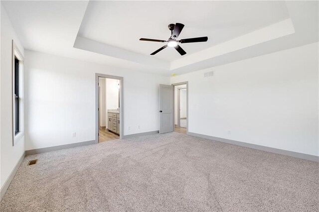 815 W Solomon Dr, Lone Jack, MO 64086 - unfurnished bedroom featuring a tray ceiling, light colored carpet, baseboards, and ceiling fan