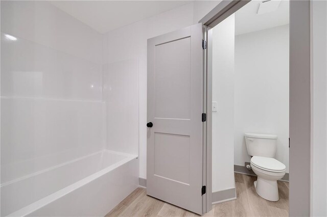 815 W Solomon Dr, Lone Jack, MO 64086 - bathroom featuring wood finished floors, toilet, and shower / bathtub combination