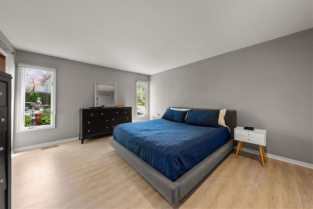 bedroom with visible vents, light wood-style flooring, and baseboards