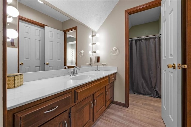 bathroom featuring wood finished floors, a textured ceiling, vanity, curtained shower, and baseboards