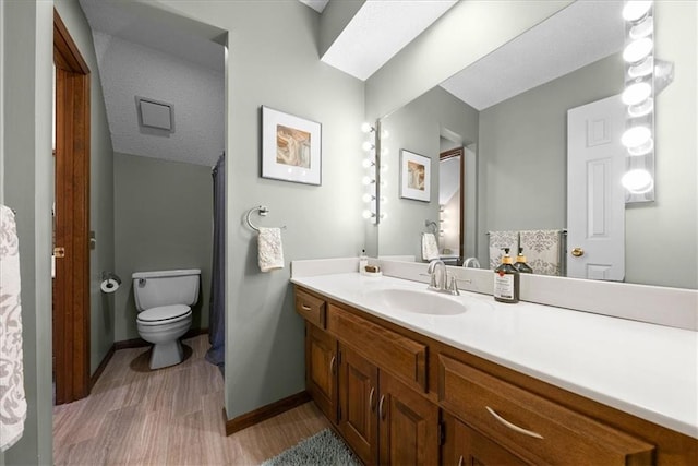 bathroom featuring toilet, vanity, wood finished floors, and baseboards