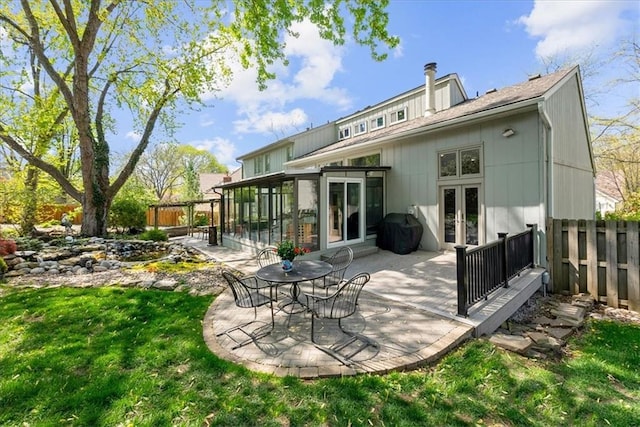 back of property with a fenced backyard, a patio area, french doors, a lawn, and a sunroom
