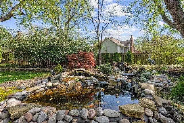 view of yard featuring a small pond and fence
