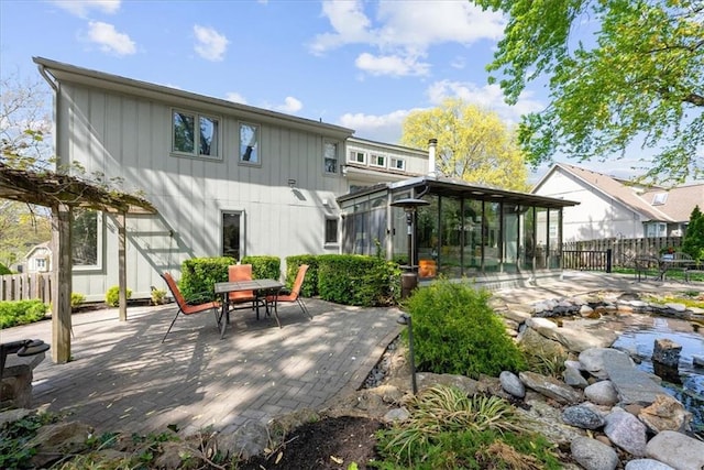 back of property featuring fence, a patio area, a sunroom, and outdoor dining space