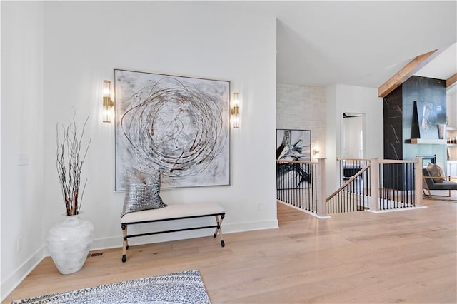 corridor with beamed ceiling, baseboards, an upstairs landing, and wood finished floors