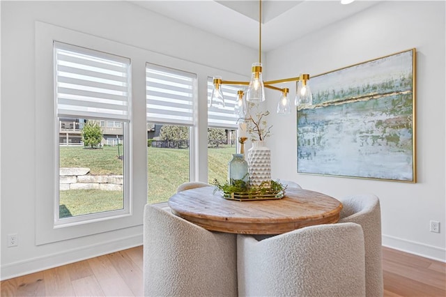 dining space with baseboards, an inviting chandelier, and wood finished floors