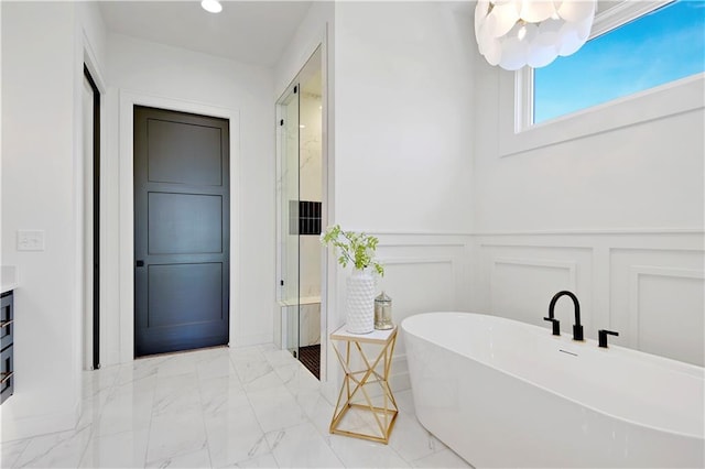 full bathroom with a walk in shower, a decorative wall, a freestanding tub, a wainscoted wall, and marble finish floor