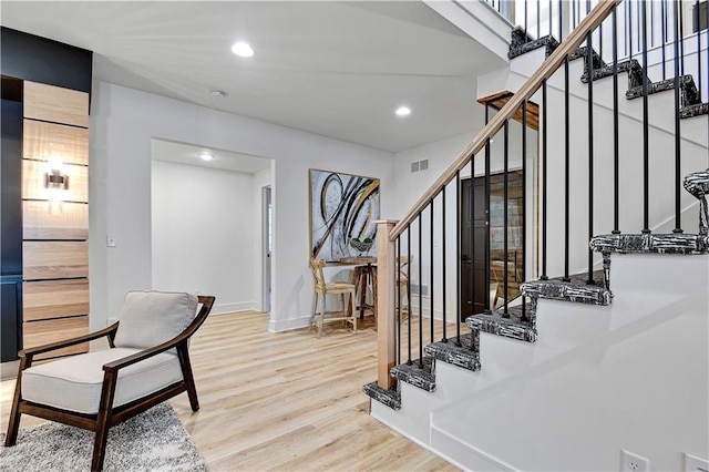 stairway with wood finished floors, baseboards, visible vents, and recessed lighting