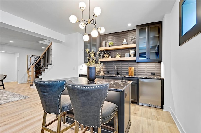 bar featuring light wood-type flooring, recessed lighting, fridge, and stairway