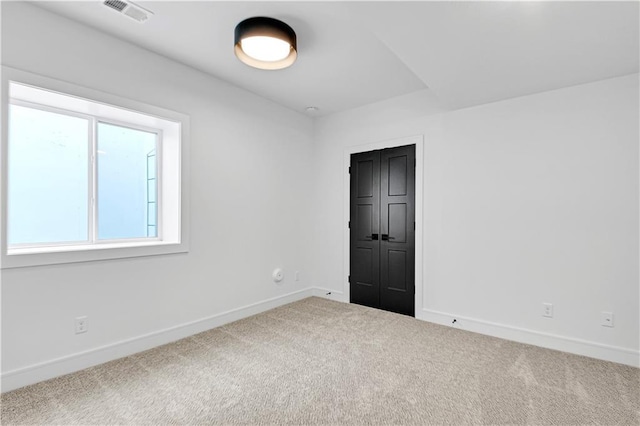spare room with carpet flooring, baseboards, and visible vents