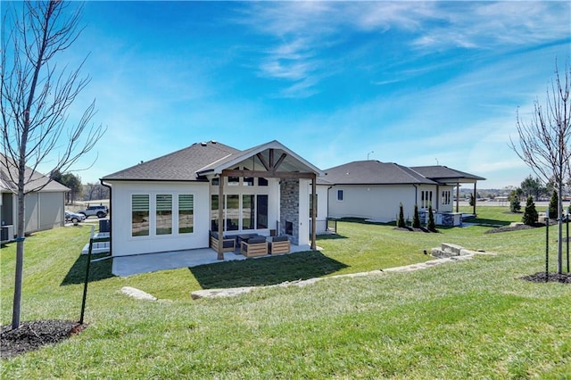 rear view of property with a shingled roof, a patio, and a lawn