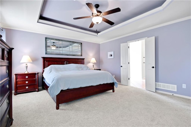 carpeted bedroom featuring crown molding, visible vents, baseboards, a raised ceiling, and a ceiling fan