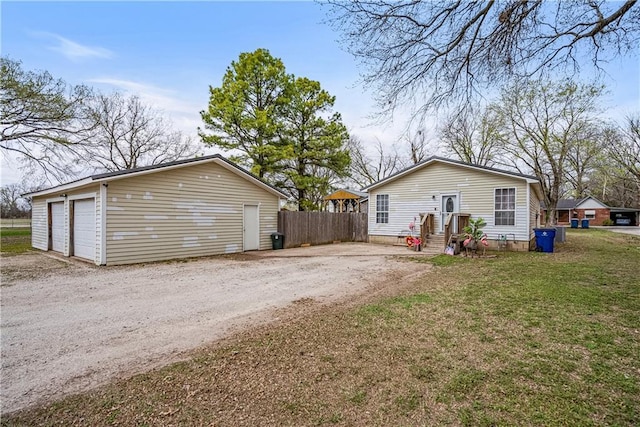 back of house with a lawn, an outbuilding, and fence