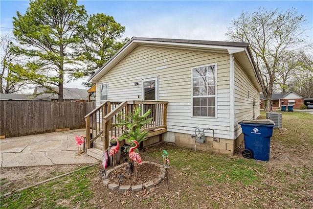 rear view of property featuring central air condition unit, fence, and a patio area